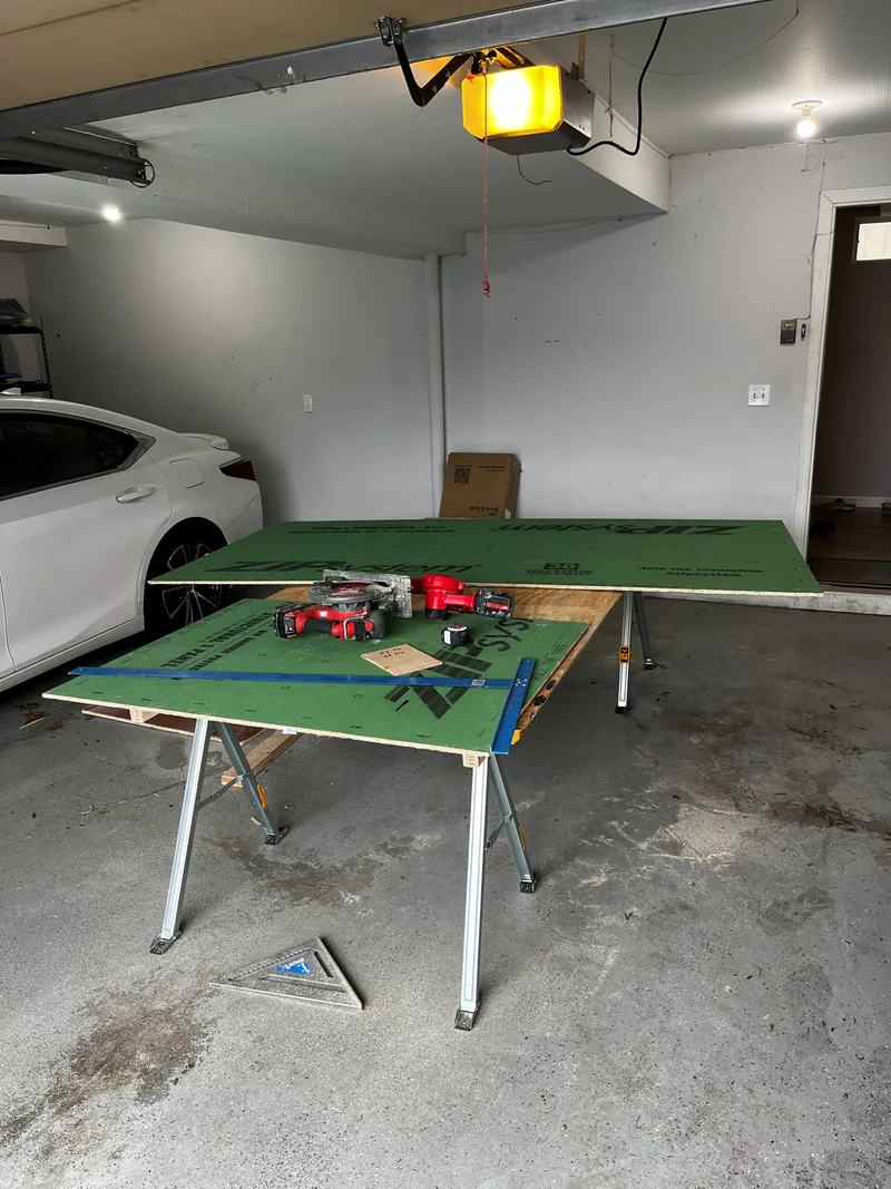 Wall backing panels laid across sawhorses in the garage and cut to size with a track saw