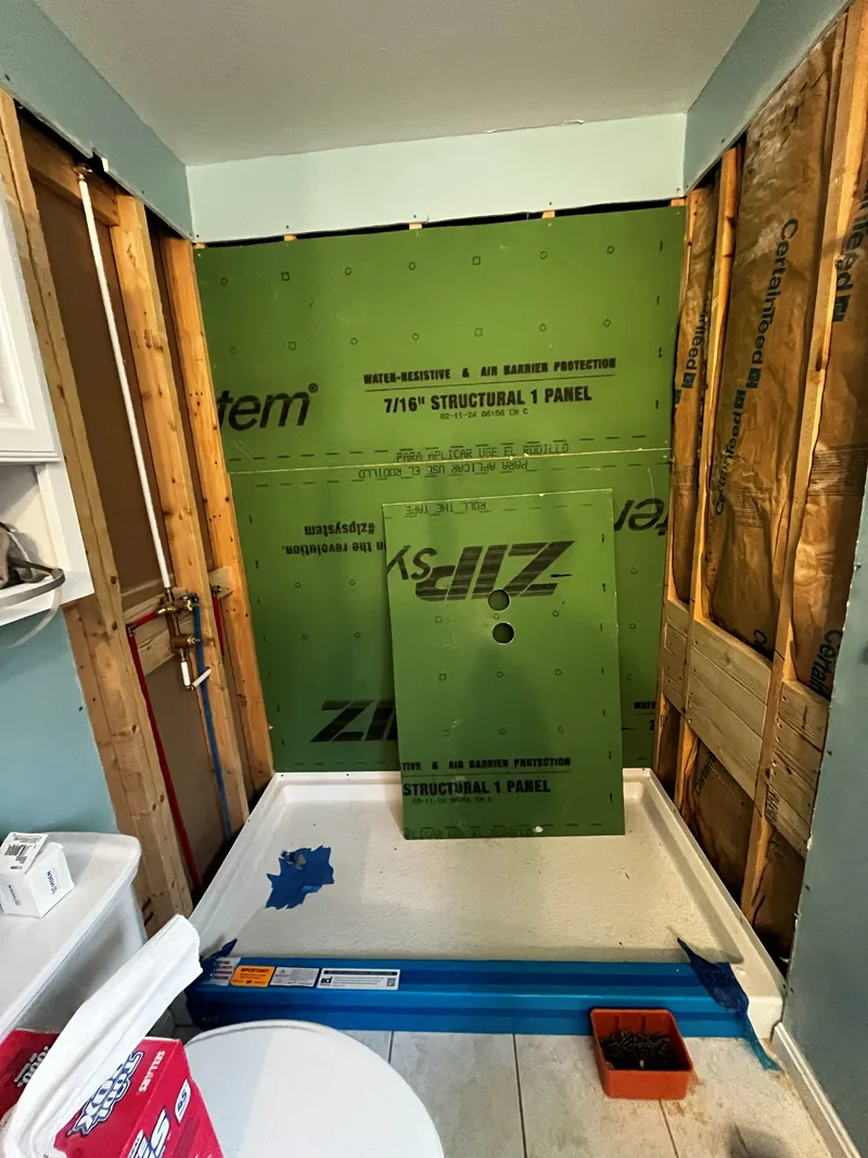 Acrylic shower base set in place with a spirit level laid across it