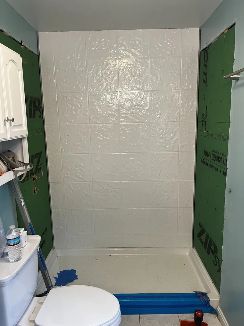 First acrylic wall panel fitted to the back wall of the shower
