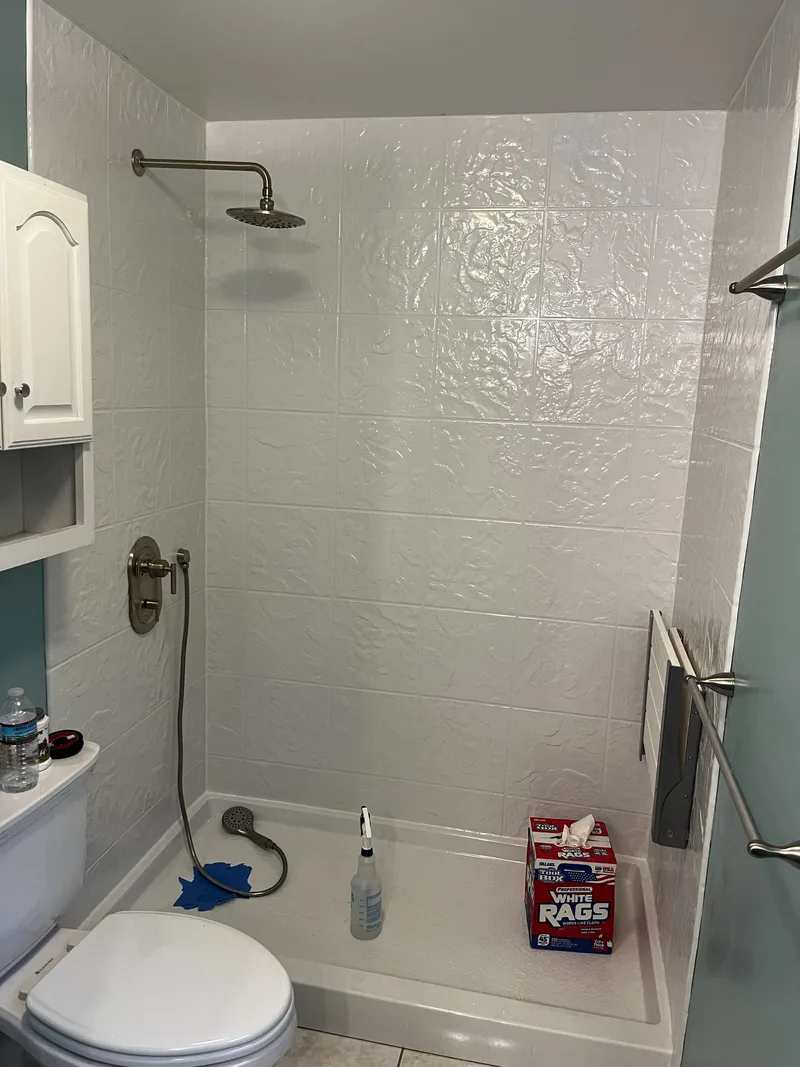 Rain head and valve trim installed on the finished acrylic wall