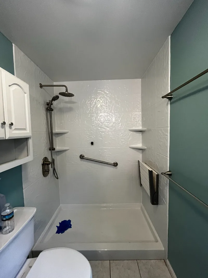 Finished acrylic shower with folding seat, grab bar and corner shelves