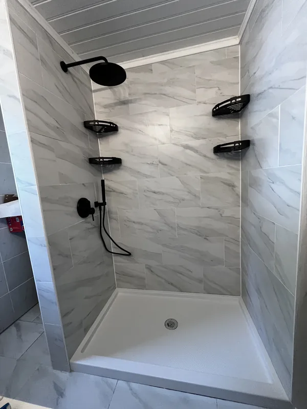 Finished shower interior — marble walls, matte black fixtures