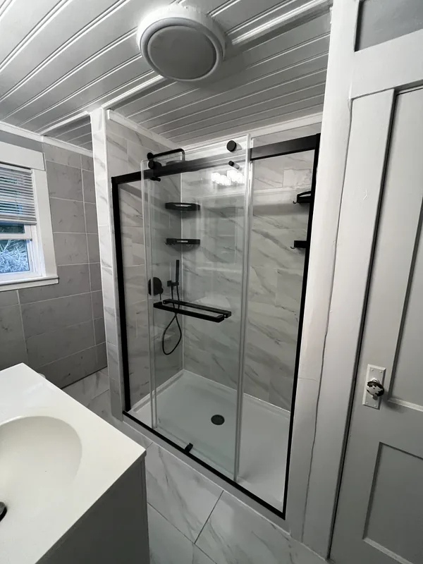 Sliding frameless glass door with matte black frame