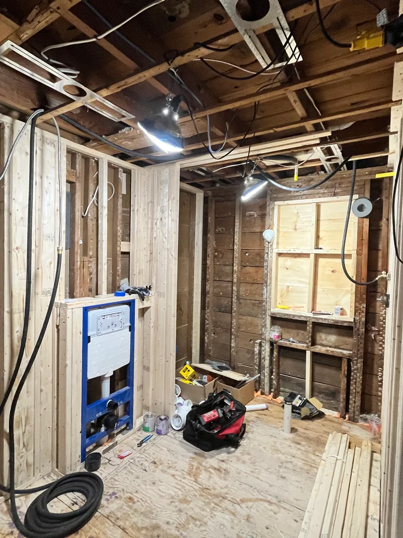 Natick bathroom stripped to studs and joists with the wall-hung toilet carrier blocked and braced