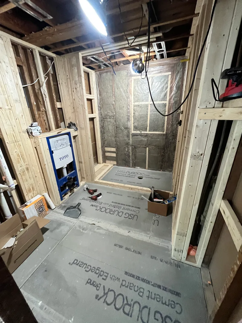 Cement board down over the joists and a pre-pitched shower pan, framing squared and carrier plumb