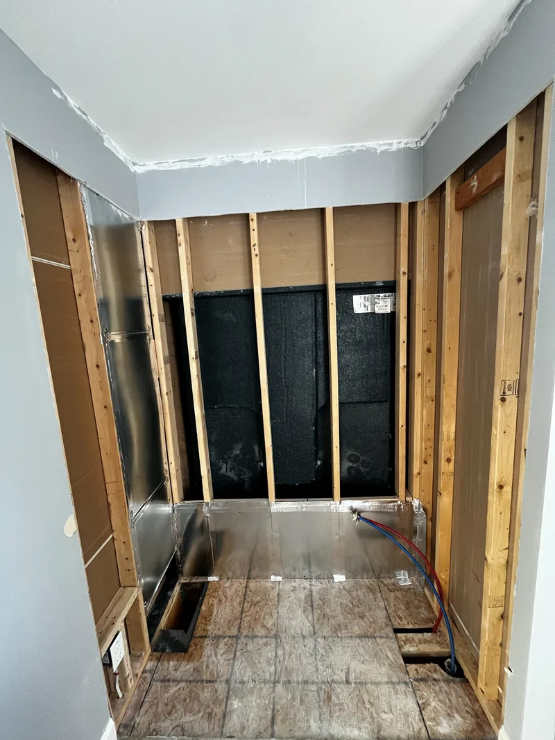 Bathroom wall open to the bare studs with new PEX supply lines run to the tub