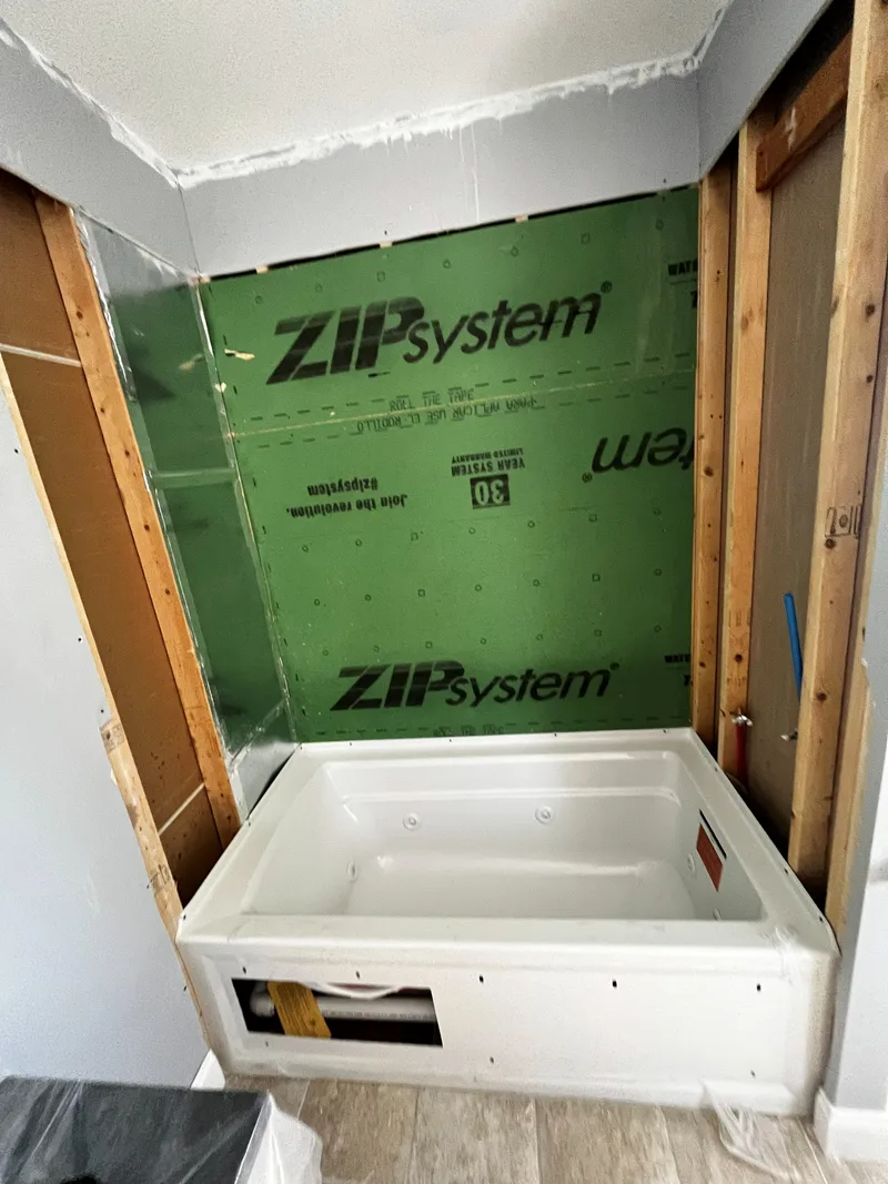 Moisture-resistant plywood backing fixed to the studs with the new acrylic tub set below