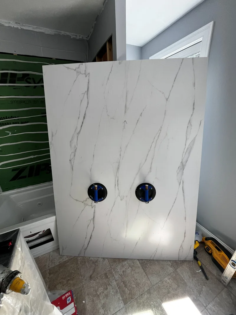 Marble-look composite panel held against the wall on two suction cups to be marked