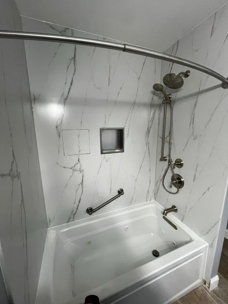 Niche set into a marble-look composite panel wall above a new tub