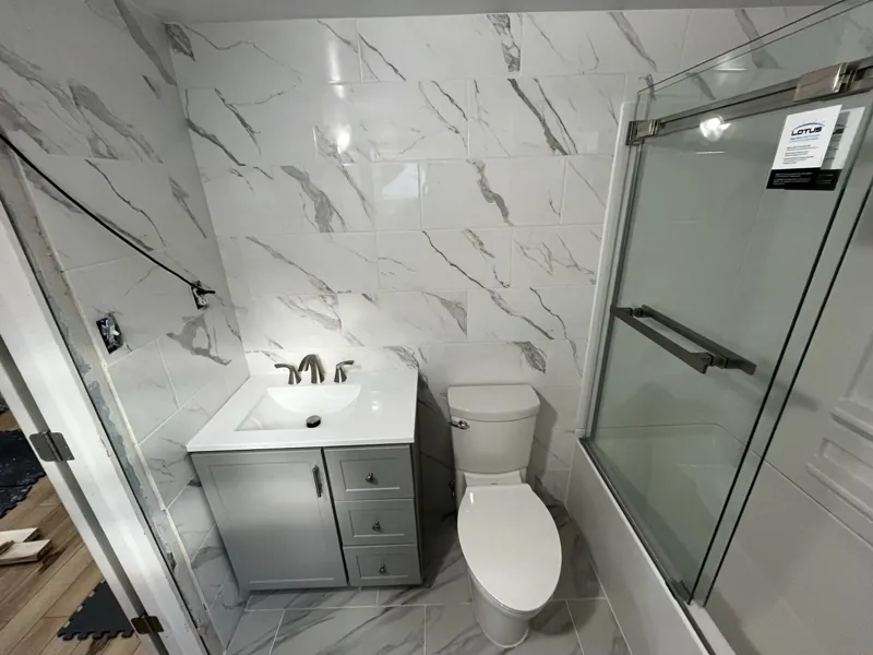 New vanity and toilet installed against tiled walls