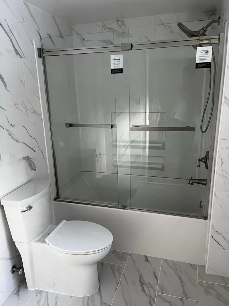 New tub with sliding glass doors against marble-look tile