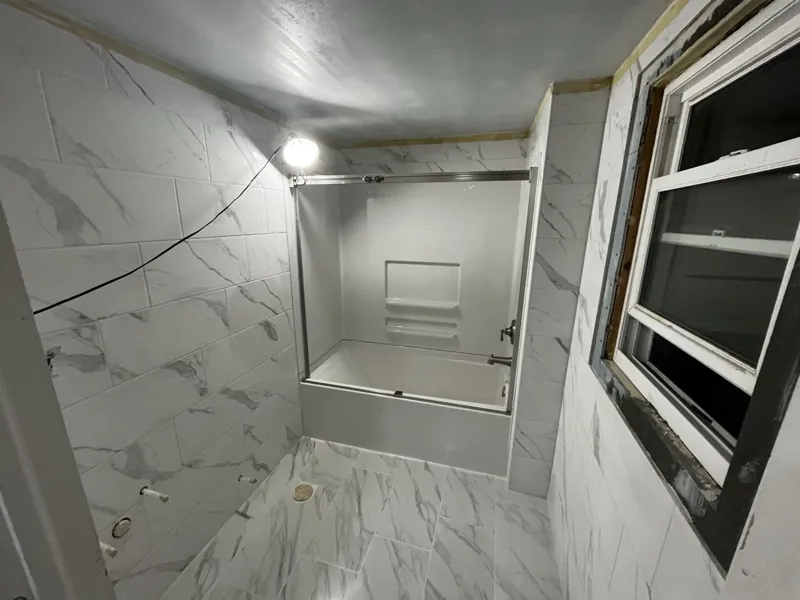 Bathroom mid-build — walls and floor tiled, fixtures not yet installed