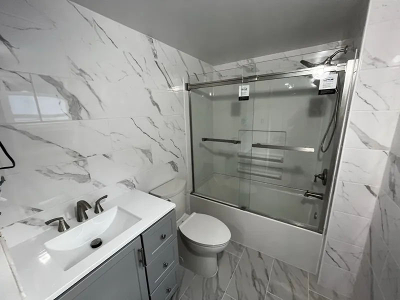 Finished bathroom with tiled walls, tub, vanity and toilet